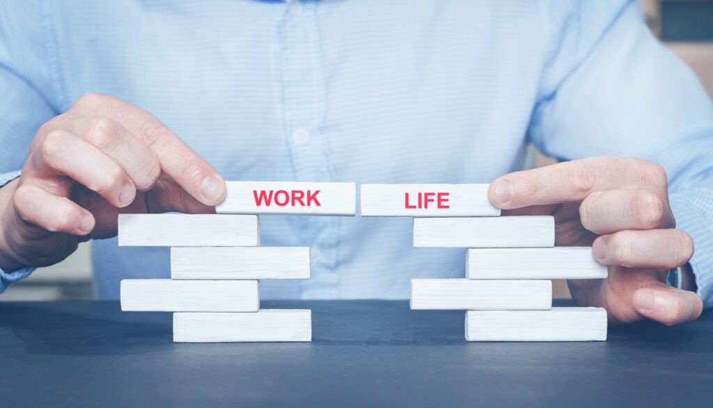 Hands carefully balancing blocks labeled work and life.