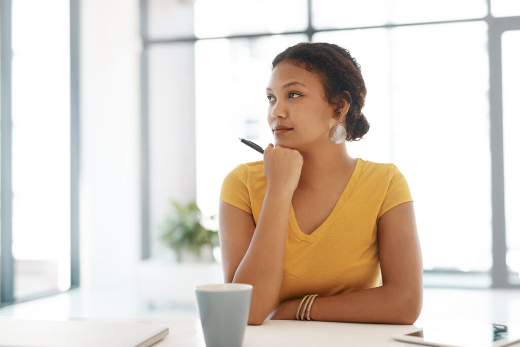 A professional woman reflecting at her desk, planning her professional development goals.