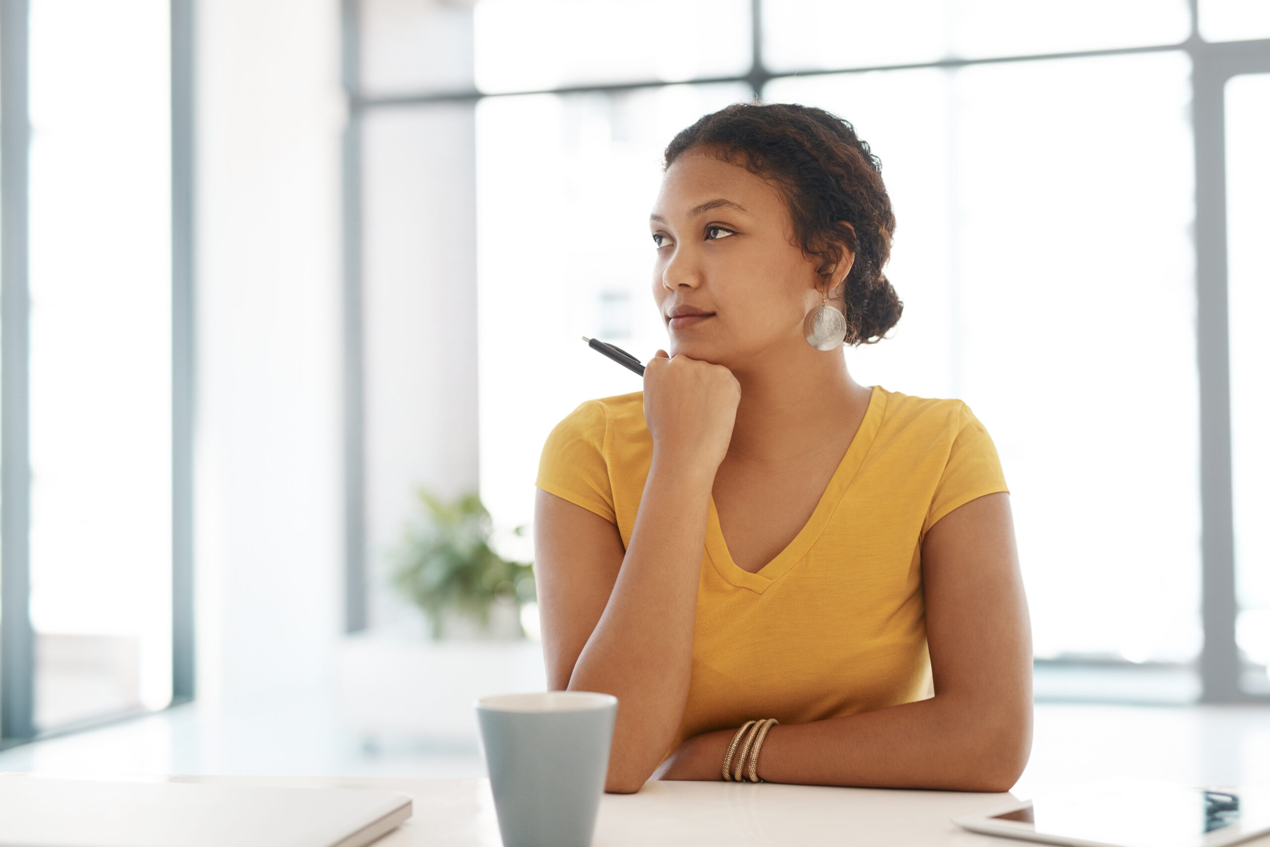 A professional woman reflecting at her desk, planning her professional development goals.