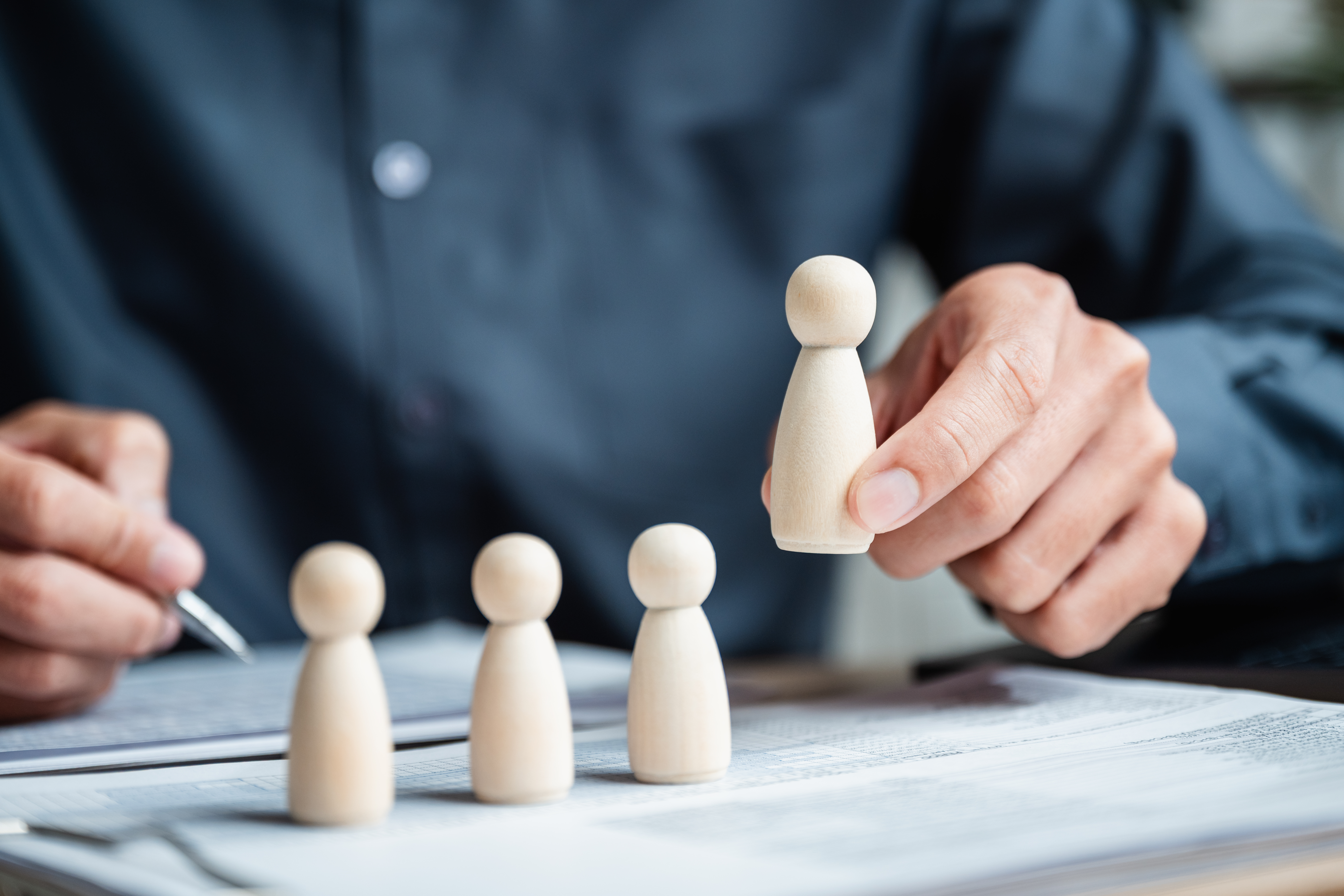 Hand selecting a figure from a group, illustrating the process of lead qualification in business strategy.